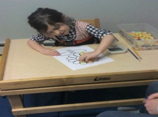 Student with poor upper body strength leaning to the right while trying to complete a craft activity