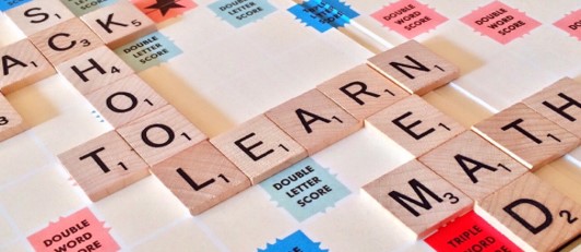 This is a photo of a Scrabble game in progress with words laid out in horizontal and vertical orientation